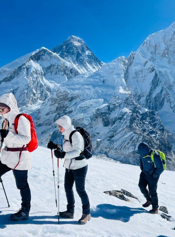 Trekkers walking across snowy terrain near Everest Base Camp with Mount Everest in the background